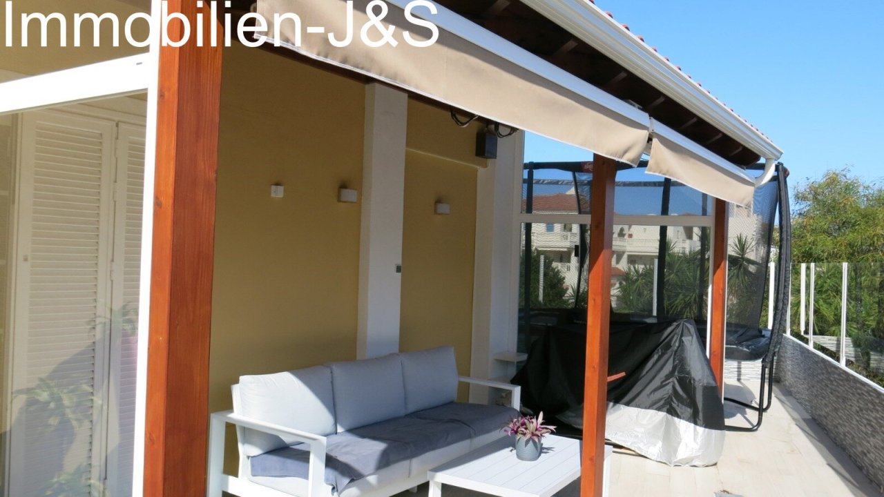 Überdachte Terrasse mit gemütlicher Lounge-Ecke und Markise