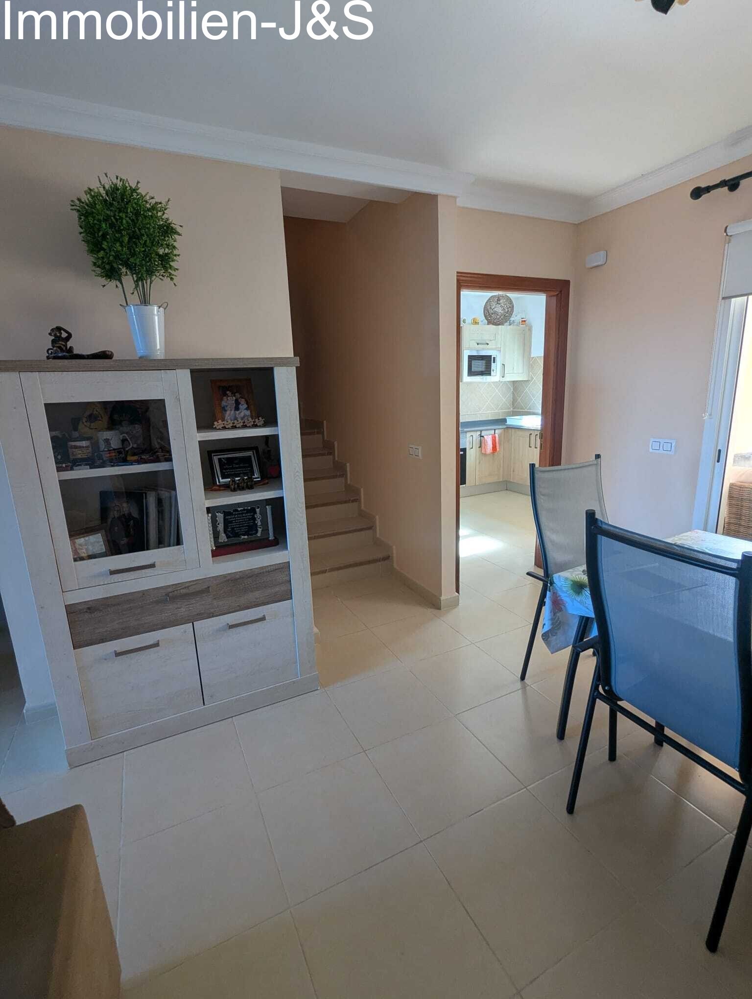 Offener Grundriss mit Blick vom Essbereich über den Flur bis in die Küche. Ein moderner Vitrinenschrank bietet praktischen Stauraum, während die Treppe in das obere Stockwerk führt Offener Grundriss mit Blick vom Essbereich über den Flur bis in die Küche. Ein moderner Vitrinenschrank bietet praktischen Stauraum, während die Treppe in das obere Stockwerk führt