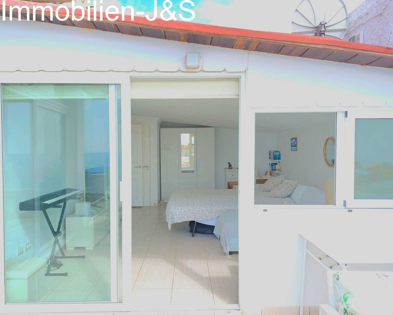 Großzügiges, helles Schlafzimmer mit direktem Zugang zur Terrasse, ausgestattet mit Einbauschränken und großen Fensterfronten für ein offenes Raumgefühl.