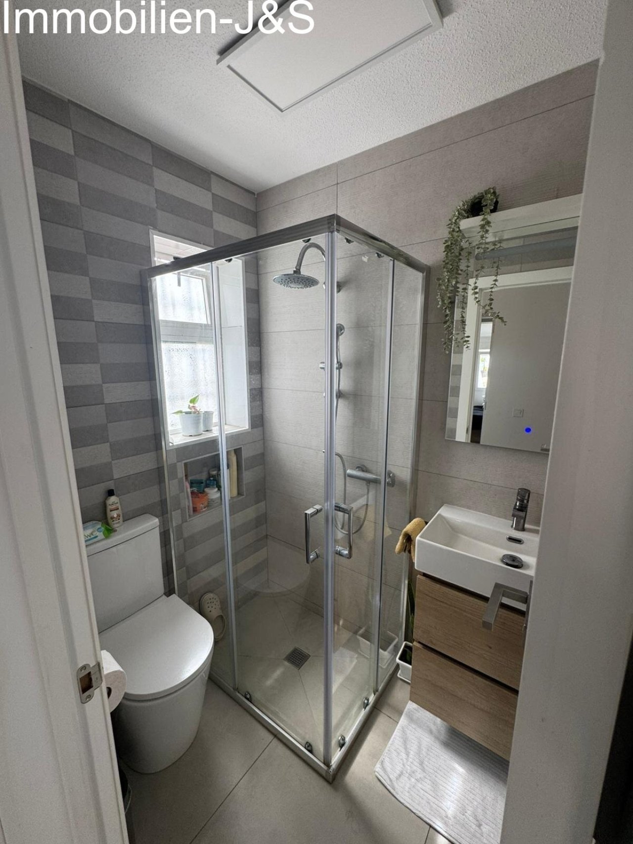 Diese Immobilie verfügt über stilvoll sanierte Badezimmer mit hochwertiger Ausstattung. Highlights sind die großzügigen, bodengleichen Duschen – teils mit Doppel-Duschkopf –, elegante Waschtische in Holzoptik und moderne Fliesendesigns. Glasbausteine und integrierte LED-Spiegel sorgen für ein helles und zeitgemäßes Ambiente.