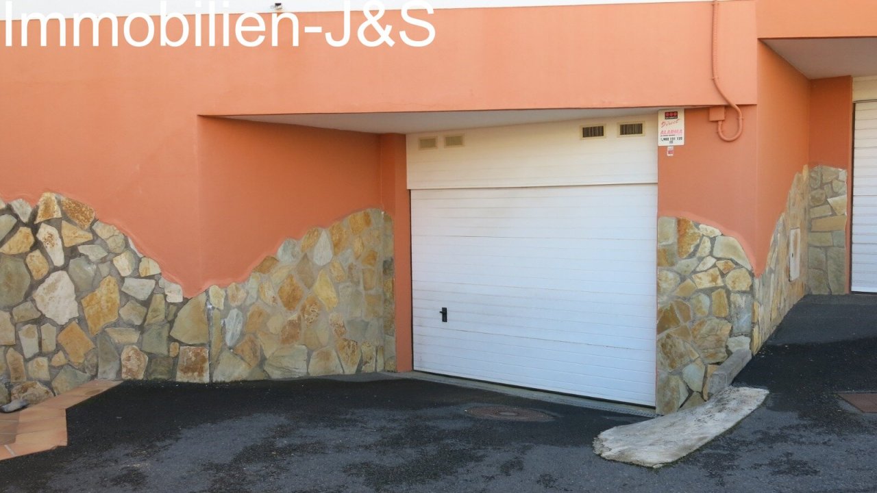 Private garage with electric roller door and natural stone accents
