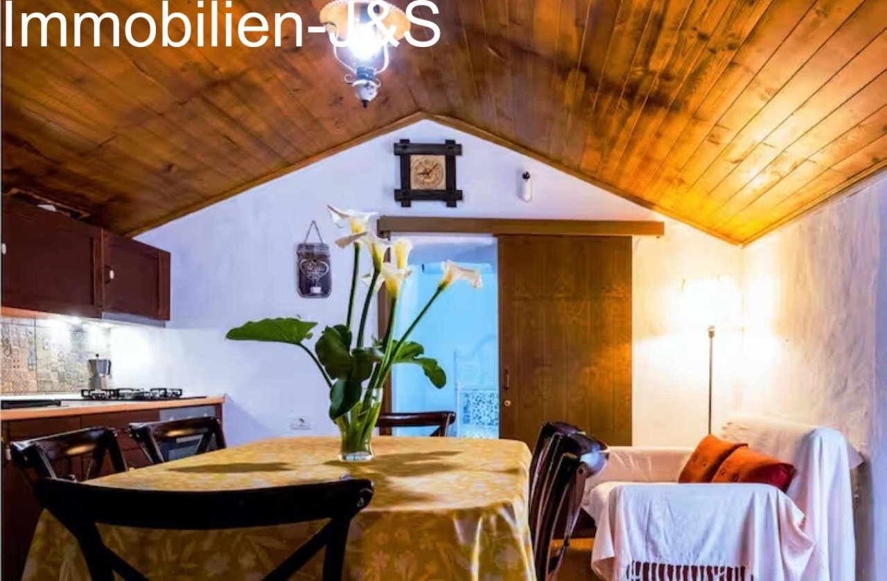 Cozy dining area with rustic wooden ceilings and a view into the bedroom.