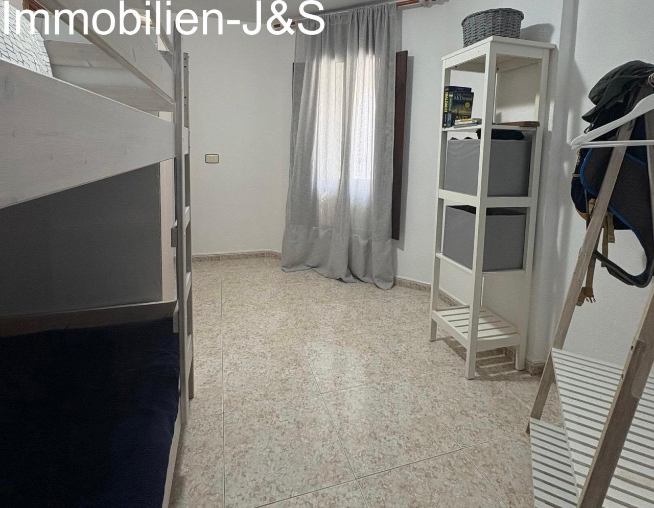 The bright and functional second bedroom is ideal as a children's or guest room, providing optimal space utilization with a sturdy bunk bed and practical shelving units.