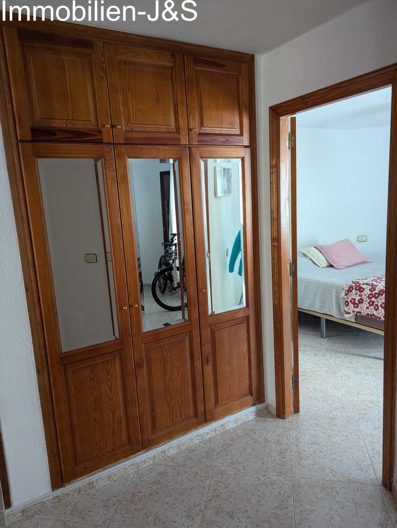 High-quality, floor-to-ceiling built-in wardrobe made of solid wood with integrated mirrored fronts – offering maximum storage space and giving the hallway a warm, spacious atmosphere.