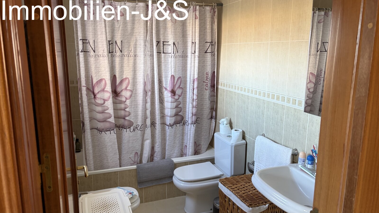 Friendly, brightly tiled bathroom with a bathtub, toilet, and practical storage space. Friendly, brightly tiled bathroom with a bathtub, toilet, and practical storage space.