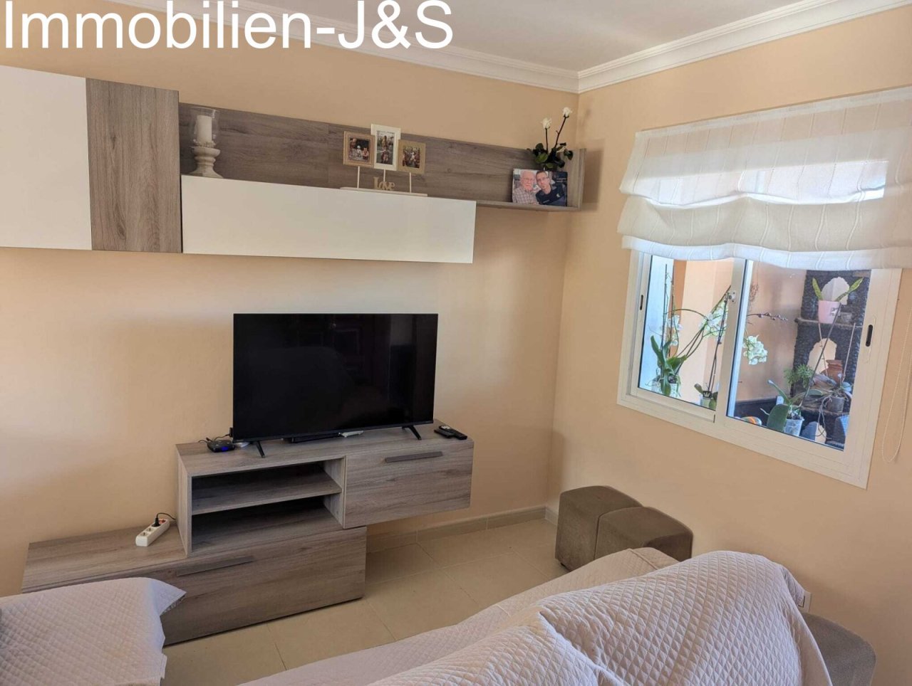 Modern living area featuring a stylish wood-look and white TV wall unit, complemented by a bright atmosphere and a view of the greenery. Modern living area featuring a stylish wood-look and white TV wall unit, complemented by a bright atmosphere and a view of the greenery.