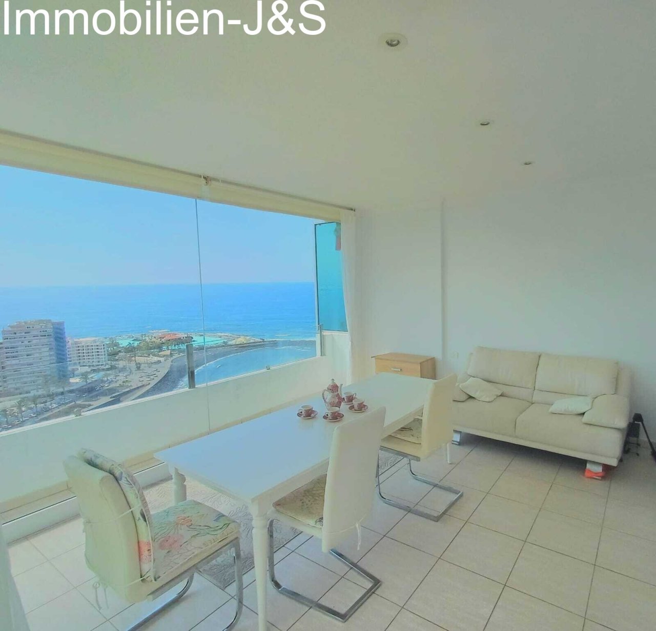 Elegant white dining area located right by the large window, offering unparalleled views of the Atlantic and the Puerto de la Cruz coastline while dining.