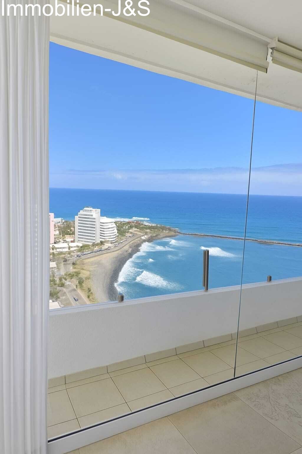 Elegant white dining area located right by the large window, offering unparalleled views of the Atlantic and the Puerto de la Cruz coastline while dining.
