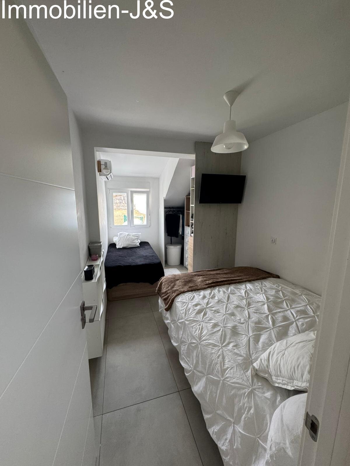 A bright and cleverly designed room, ideal as a children's room, guest room, or home office. It offers space for two beds, features its own air conditioning, and provides optimal storage with custom shelving and dressers.