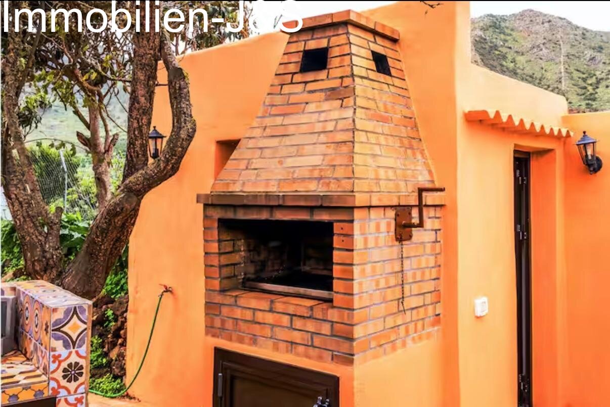 Cocina exterior con detalles en mosaico y barbacoa de obra en el jardín.