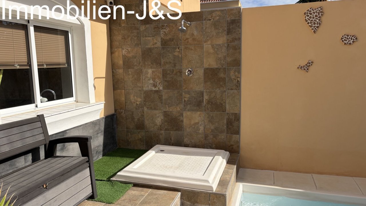 Moderna zona exterior con piscina privada, una elegante ducha al aire libre alicatada y una decoración de pared que muestra la silueta de las Islas Canarias. Un acogedor banco invita al descanso. Moderna zona exterior con piscina privada, una elegante ducha al aire libre alicatada y una decoración de pared que muestra la silueta de las Islas Canarias. Un acogedor banco invita al descanso.