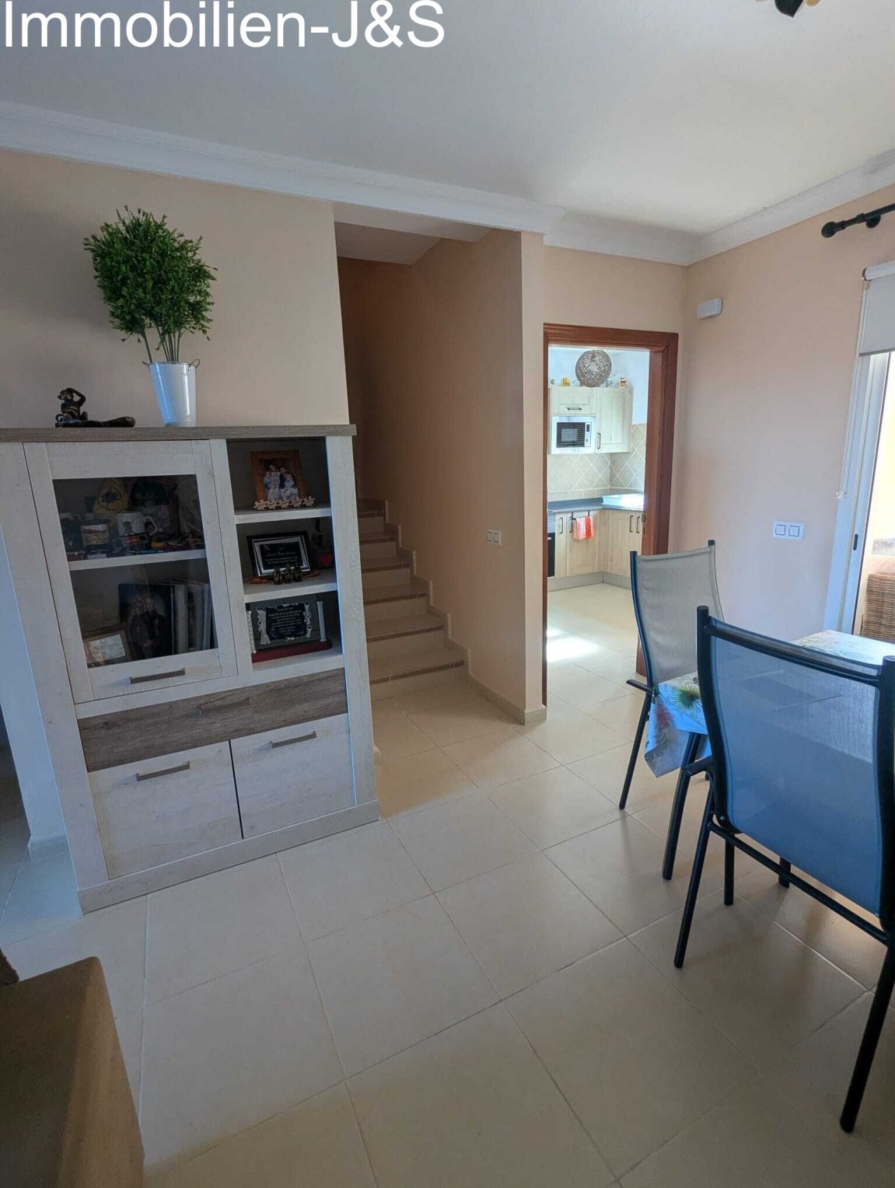 Planta abierta con vistas desde el comedor a través del pasillo hacia la cocina. Una moderna vitrina ofrece práctico espacio de almacenamiento, mientras que la escalera conduce a la planta superior. Planta abierta con vistas desde el comedor a través del pasillo hacia la cocina. Una moderna vitrina ofrece práctico espacio de almacenamiento, mientras que la escalera conduce a la planta superior.