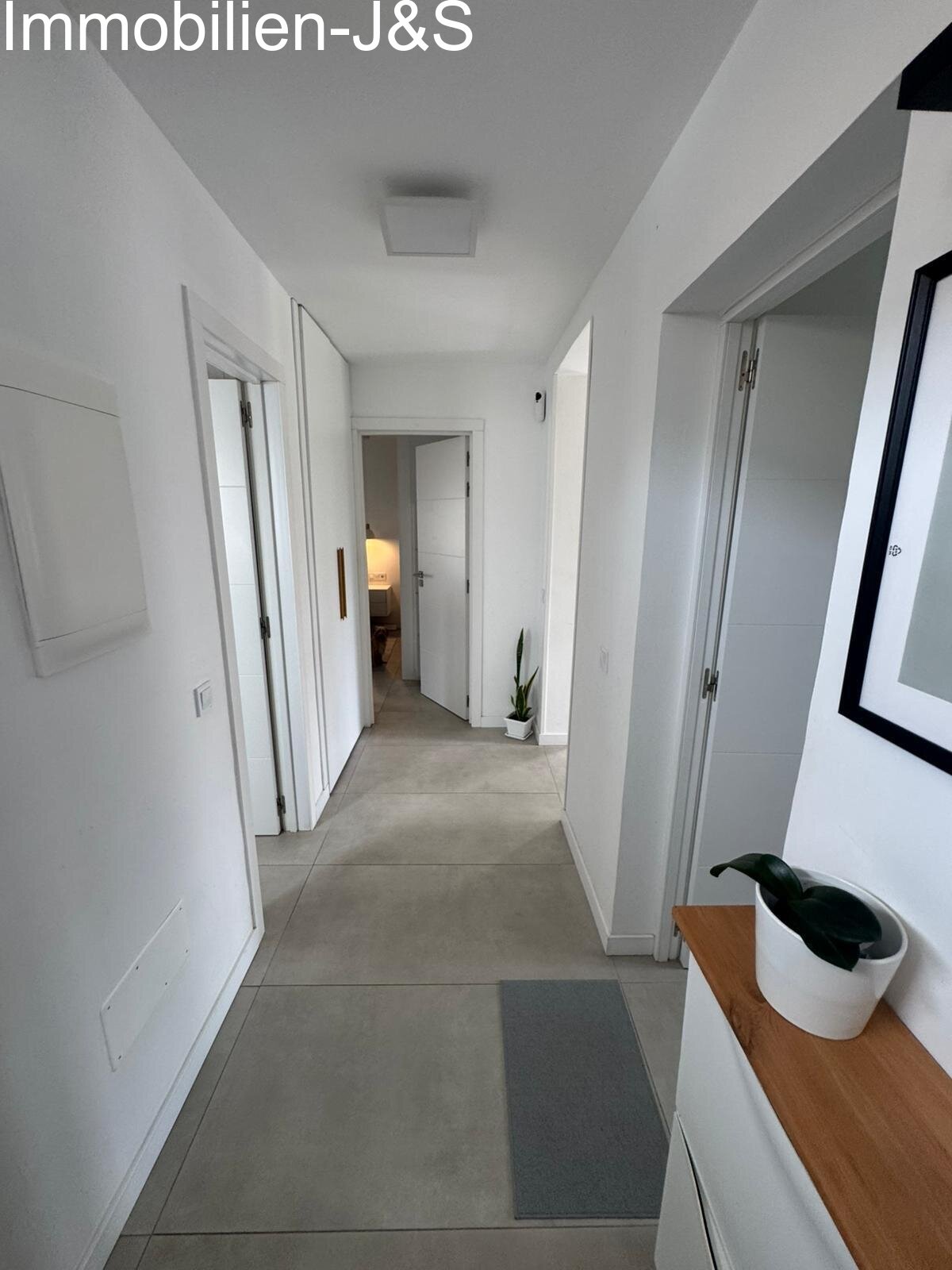 Una zona de entrada luminosa y agradable que transmite de inmediato una sensación de hogar. El pasillo conecta las estancias de forma eficiente y ofrece un discreto espacio de almacenaje gracias a sus elegantes armarios empotrados blancos. El diseño minimalista y los suelos claros resaltan el ambiente moderno de toda la vivienda